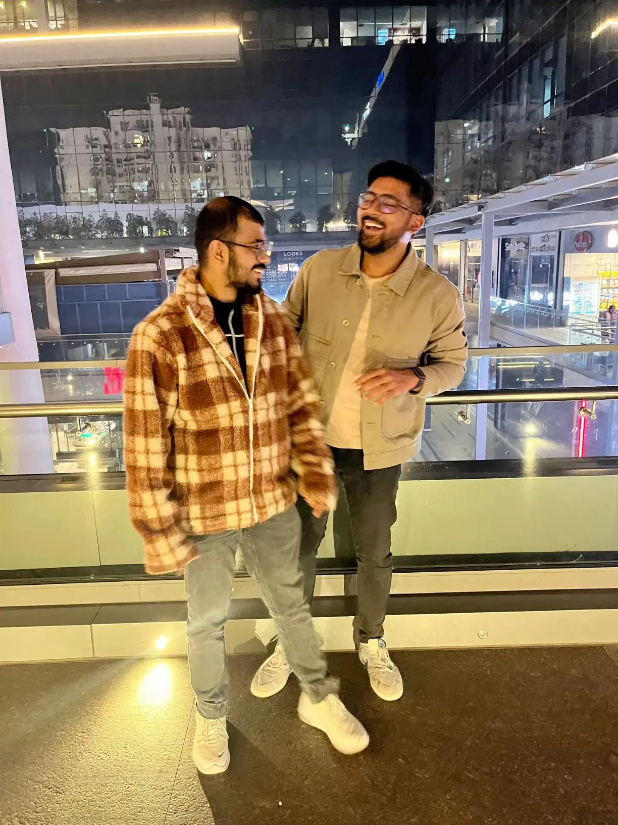 two men standing next to each other in front of a window