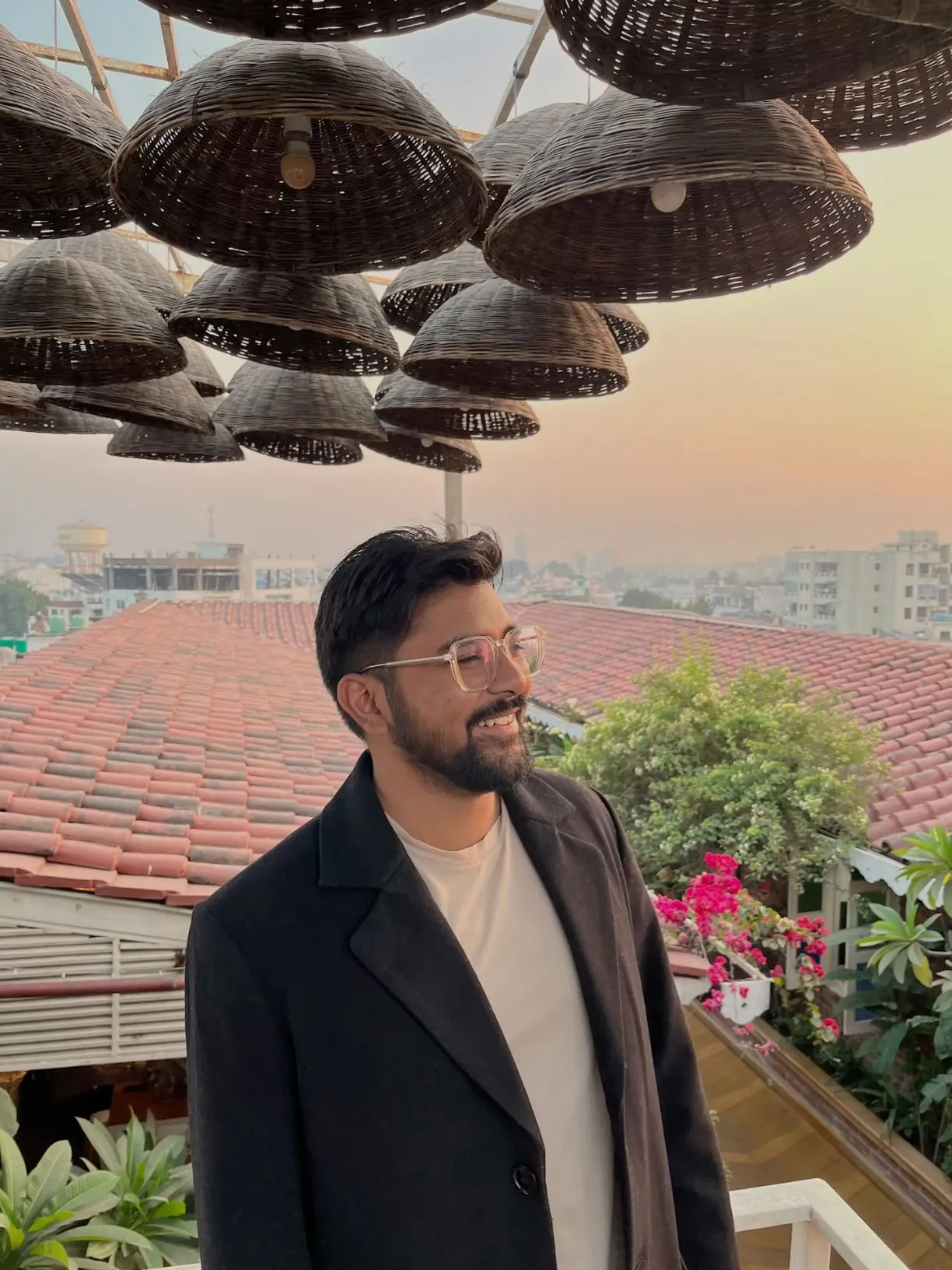 a man wearing glasses standing on top of a roof with lots of lights hanging from the ceiling