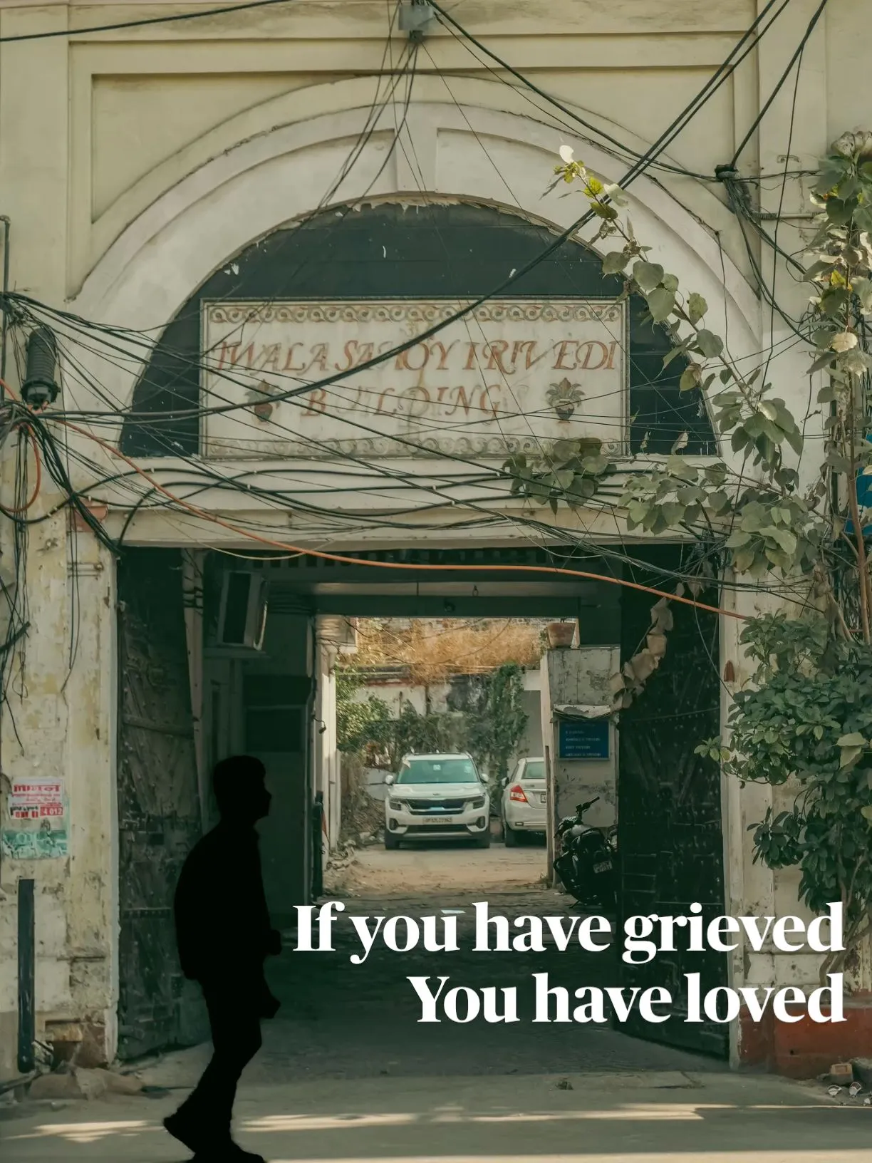 a man walking down the street in front of a building with an advertisement on it that reads if you have grieved, you have loved