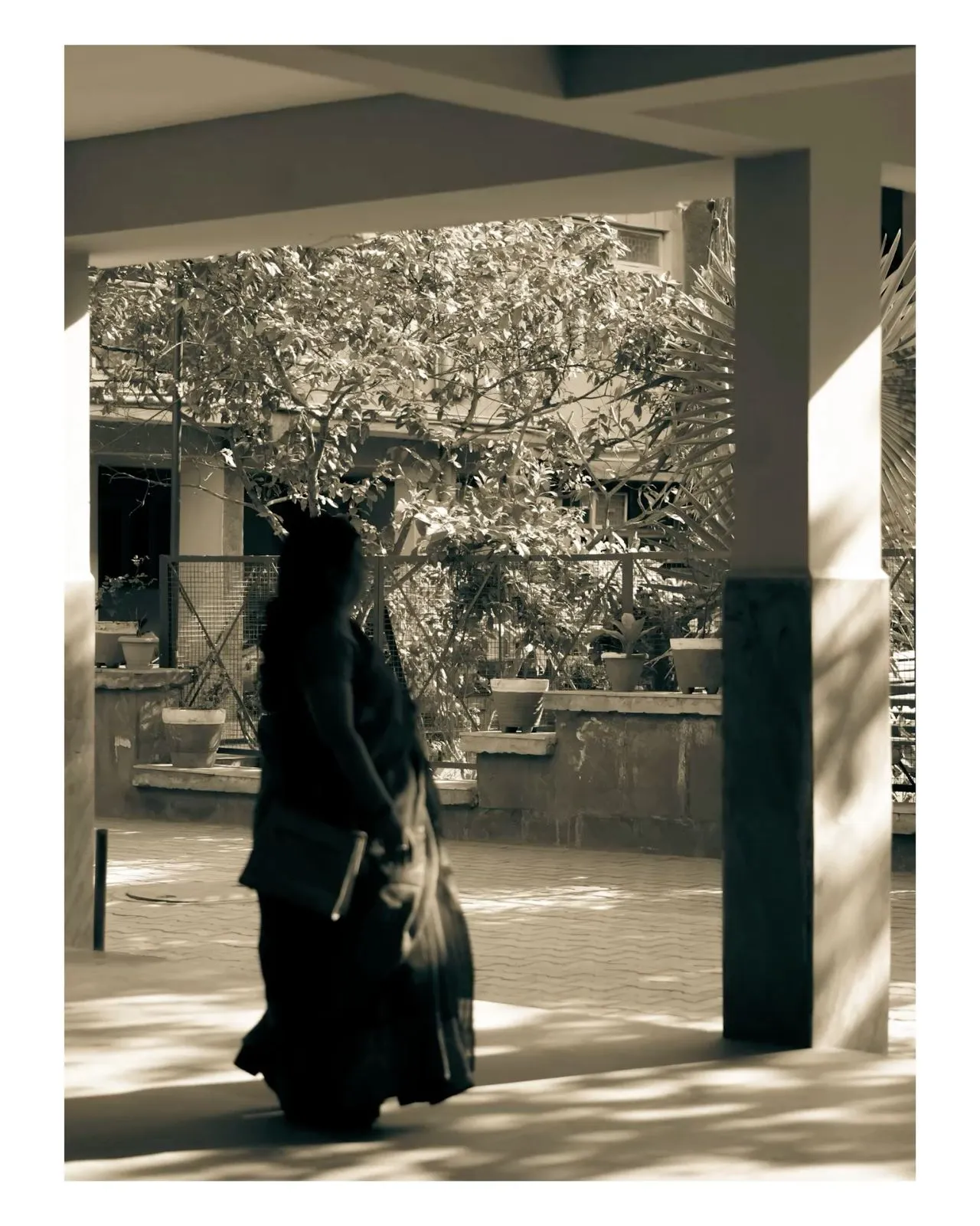 a woman is walking down the sidewalk with her luggage in hand and trees in the background