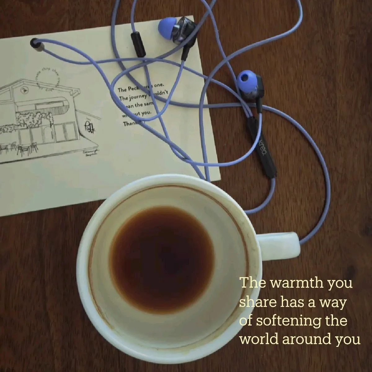 a cup of coffee sitting on top of a wooden table next to a piece of paper