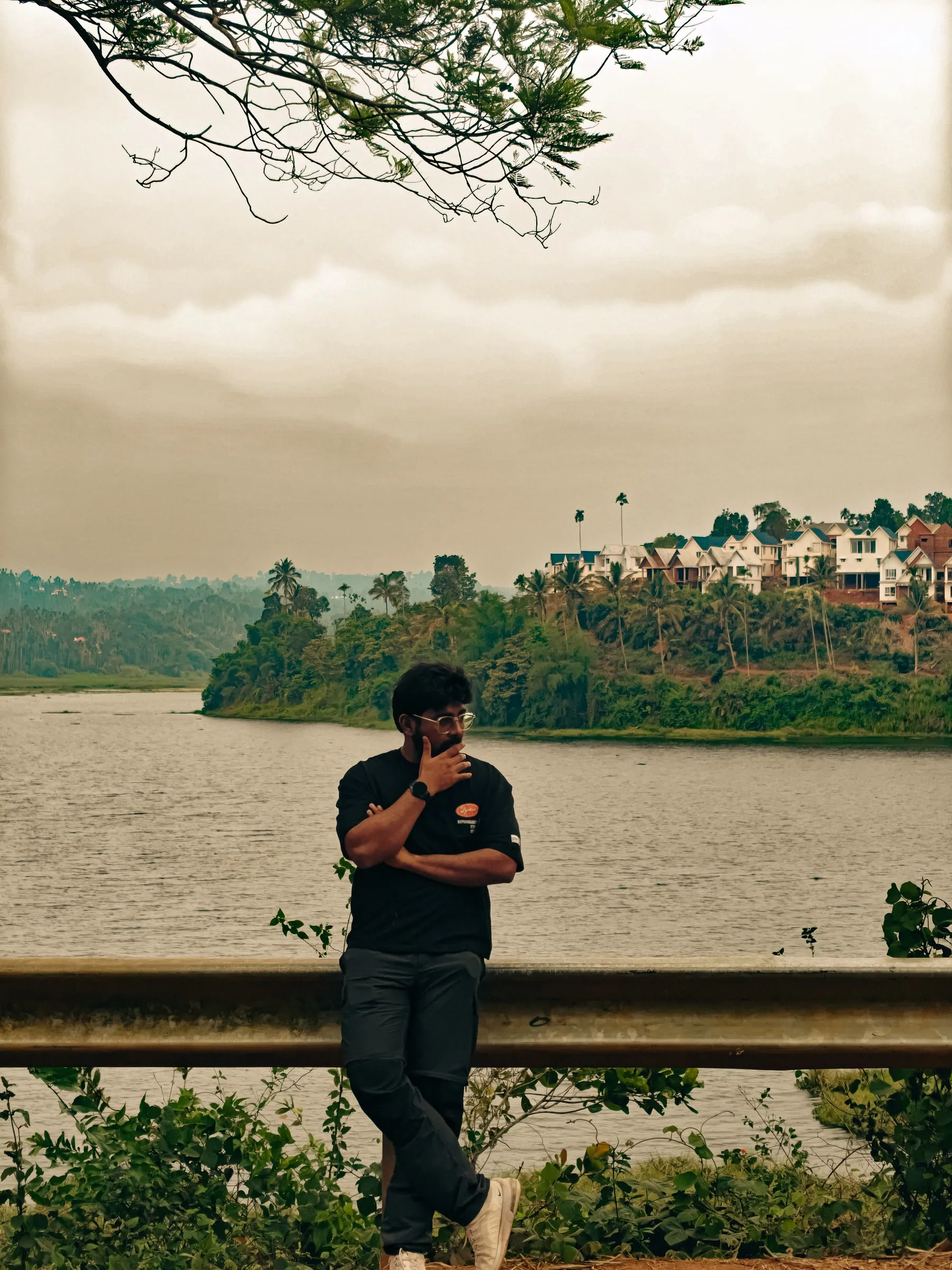 a man is sitting on a bench by the water looking at his cell phone while he looks off into the distance