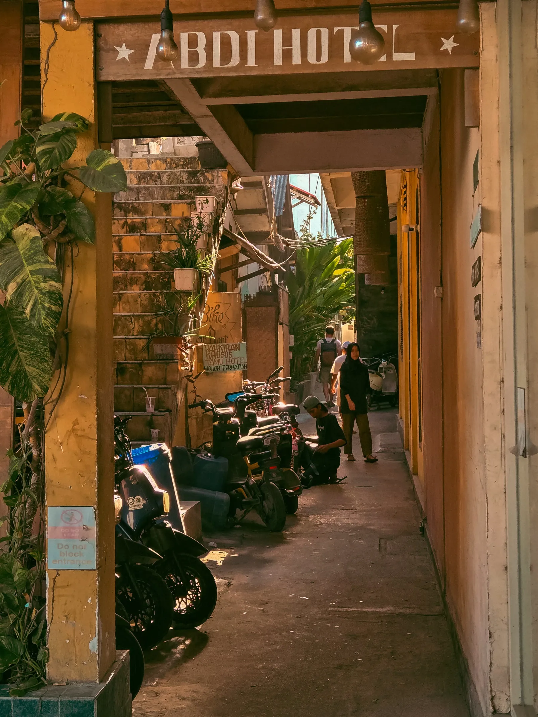 motorcycles are lined up on the side of an alleyway in front of a hotel