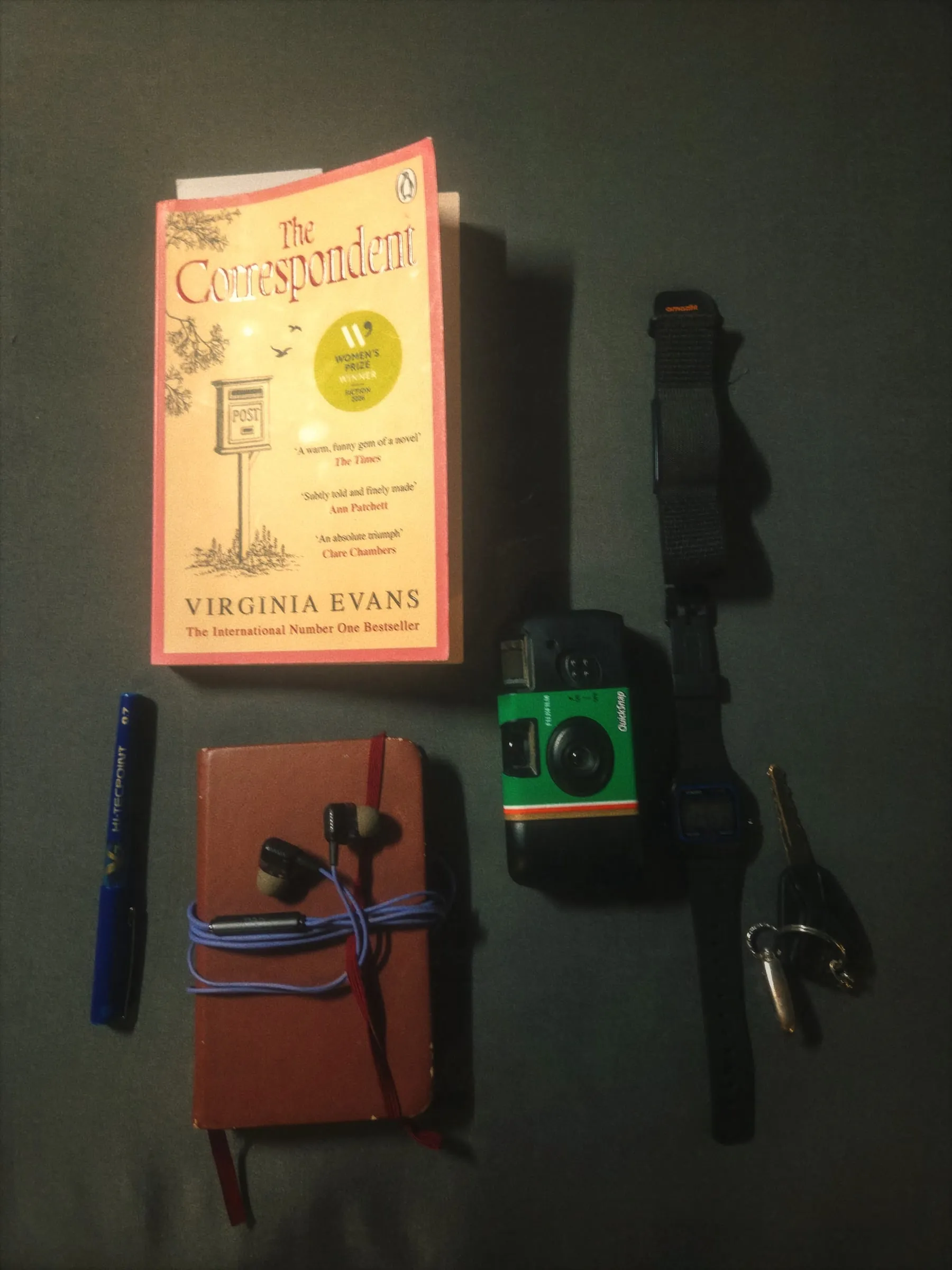 the contents of a camera, book and other items laid out on a table