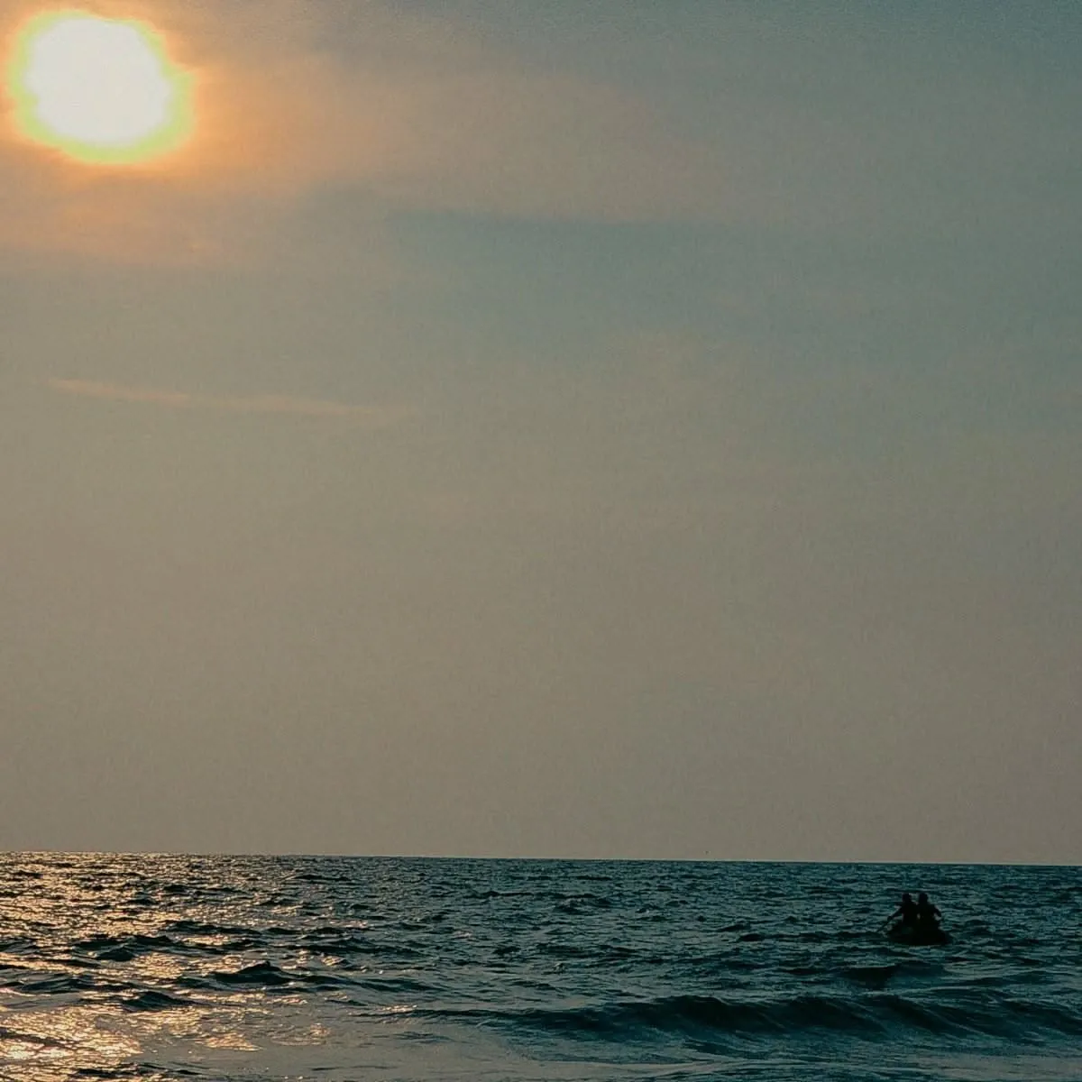 a person riding a surfboard in the ocean at sunset